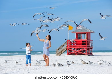 Young mother and her little son feeding seagulls on tropical beach, Florida summer holiday vacation - Powered by Shutterstock