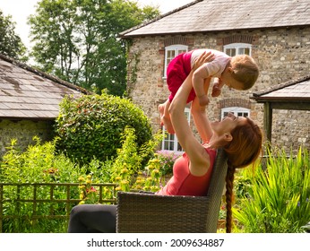 A Young Mother And Her Lovely Baby Girl Enjoy A Sunny Day In Their Holidays Cottage In Dorset, UK