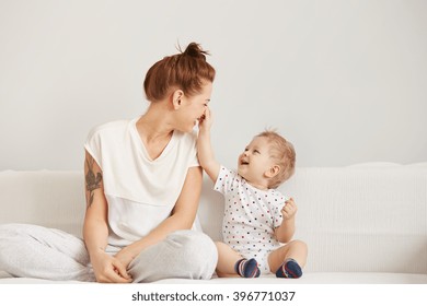 Young mother and her one years old little son dressed in pajamas are relaxing   playing in the bedroom at the weekend together  lazy morning  warm   cozy scene  Selective focus 