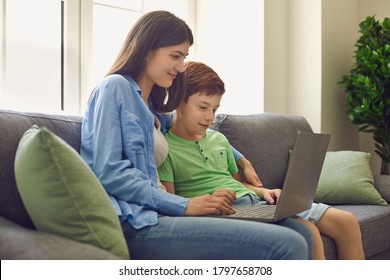 Young Mother And Her Son Talking To Teacher From Home. Parent And Child Watching Online Lesson On Laptop Computer