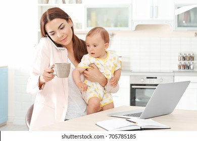 Young Mother Holding Baby While Talking On Phone At Home