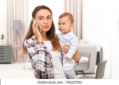 Young Mother Holding Baby While Talking On Phone At Home