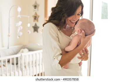 Young mother holding her baby in the bedroom - Shutterstock ID 490357858