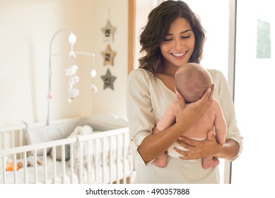 Young Mother Holding Her Baby In The Bedroom