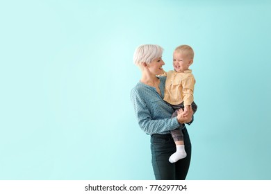 Young Mother Holding Her Baby On Color Background