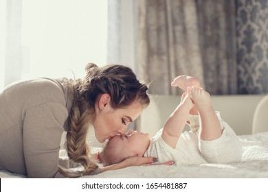 Young Mother Holding Her Newborn Child. Mom Nursing Baby. Woman And New Born Boy Relax. Nursery Interior Family At Home. Portrait Of Happy Mother And Baby