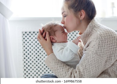 Young Mother Holding Her Newborn Child. Mom Nursing Baby. Woman And New Born Boy Relax. Nursery Interior Family At Home. Portrait Of Happy Mother And Baby