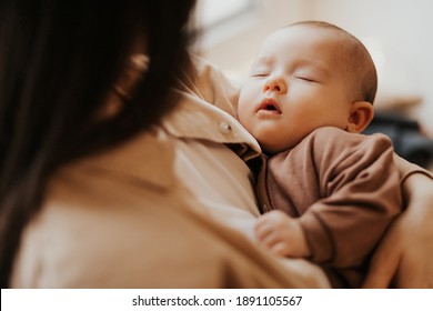 Young mother holding her newborn child. mother's care baby. Woman and new born girl relax. Baby sleeping on mom's arms