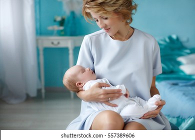 Young Mother Holding Her Newborn Child. Mom Nursing Baby. Woman And New Born Boy Relax. Nursery Interior. Mother Breast Feeding Baby. Family At Home. Portrait Of Happy Mother And Baby