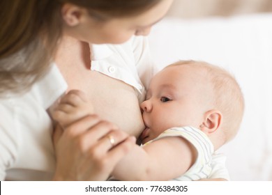 Young mother holding her newborn child. Mom nursing baby. Pretty woman breast feeding kid
