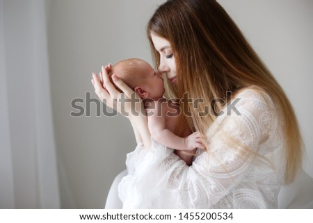 Young mother holding her newborn child. Mom nursing baby. Woman and new born boy relax. Nursery interior. Mother breast feeding baby. Family at home. Portrait of happy mother and baby