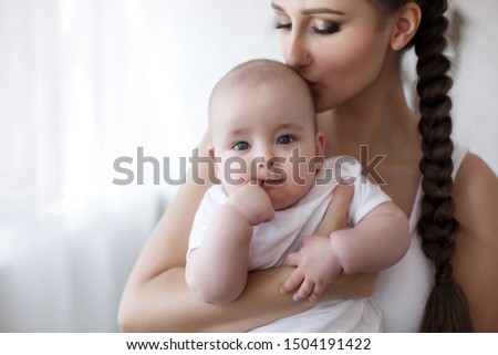 Young mother holding her newborn child. Mom nursing baby. Woman and new born boy relax. Nursery interior. Mother breast feeding baby. Family at home. Portrait of happy mother and baby
