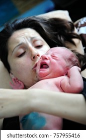 Young Mother Holding Her Newly Born Baby. There Is A Umbilical Cord Still Connect. Baby Is Crying