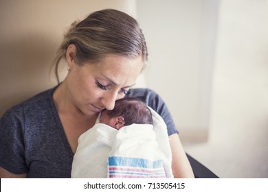 Young mother holding her Premature newborn baby who is being treated in the hospital
