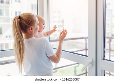 Young Mother Holding And Hugging Newborn Baby Son At Home. Family Relaxing On Balcony.