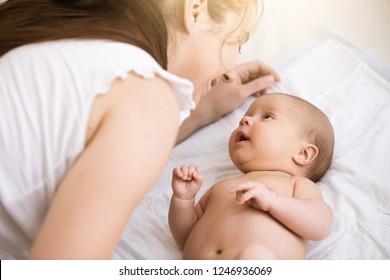 Young mother holding a newborn baby. Mom talks and laughs with her newborn son at home bedroom. Lifestyle happy multiracial family concept