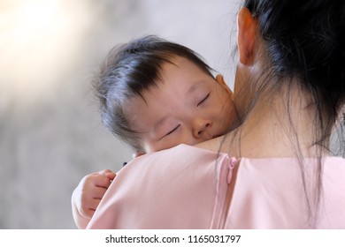 Young Mother Holding Sweet Baby Boy  And Singing A lullabies for Her Son To Sleep, On Concrete Wall Loft Style Background.