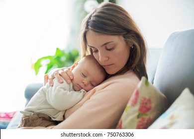 Young mother, holding tenderly her newborn baby boy, close portrait