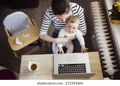 Young mother in home office with computer and her daugher