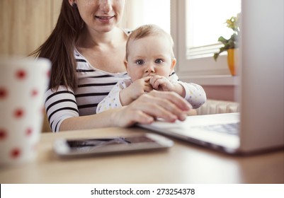 Young mother in home office with computer and her daugther