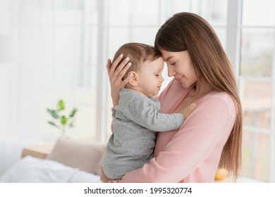 Young mother hugging embracing little son daughter kid child with love and care. Babysitter nanny holding toddler newborn baby infant. Motherhood and adoption concept