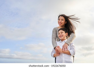 Young mother hugging her child against a bright blue sky with clouds. Latin people. Copy space. - Powered by Shutterstock