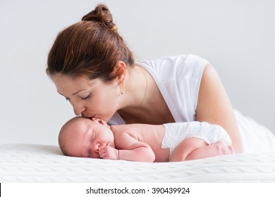 Young mother hugging her newborn child. Mom nursing baby. Woman and new born boy relax in a white bedroom. Family at home. Love, trust and tenderness concept. Bedding and textile for nursery. - Powered by Shutterstock