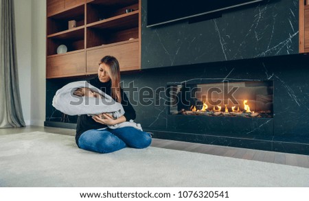 Mother hugging her baby in front of fireplace