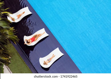 Young Mother, Kids Relax On Sun Beds At Swimming Pool In Luxury Spa Resort Or Villa. Top View. Tourism Industry Crisis After Covid 19 Coronavirus Pandemic. Travel Lifestyle On Family Summer Vacation.