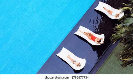 Young Mother, Kids Relax On Sun Beds At Swimming Pool In Luxury Spa Resort Or Villa. Top View. Tourism Industry Crisis After Covid 19 Coronavirus Pandemic. Travel Lifestyle On Family Summer Vacation.