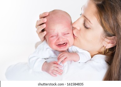 Young mother kissing her crying newborn baby