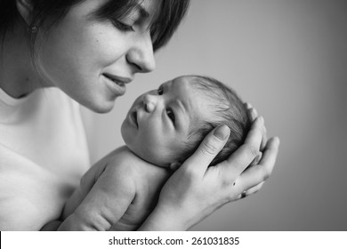 Young Mother Kissing Her Little Newborn Baby. Black And White