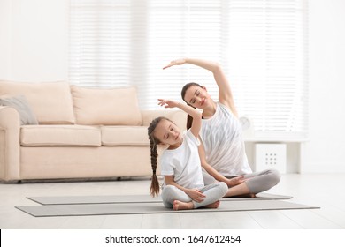 Young mother with little daughter practicing yoga at home - Powered by Shutterstock