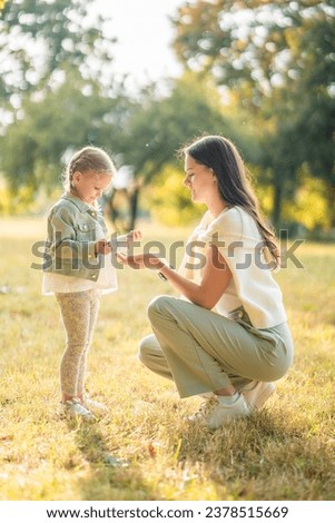 Young mother and little daughter spending time together in autumn park of Prague, Europe. High quality photo