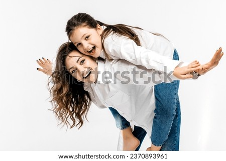 Young mother and little girl playing on a white background. The concept of advertising positive, happy sincere emotions, clothes and a happy carefree life.