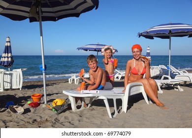 young mother, little son and daughter sitting on lounge on beach and eating pizza, focus on boy