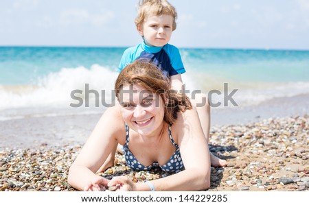 Young mother and little son having fun on beach vacation. Selective focus on woman