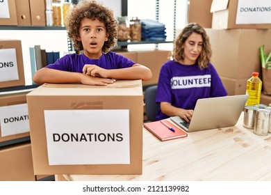 Young Mother With Little Son Wearing Volunteer T Shirt At Donations Stand Scared And Amazed With Open Mouth For Surprise, Disbelief Face 