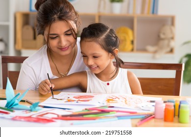 Young mother looking how her daughter drawing picture