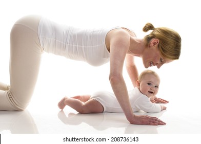Young mother makes with her 6 month old daughter postnatal exercises, isolated against white background. She kneels on the ground and makes about the baby pushups.