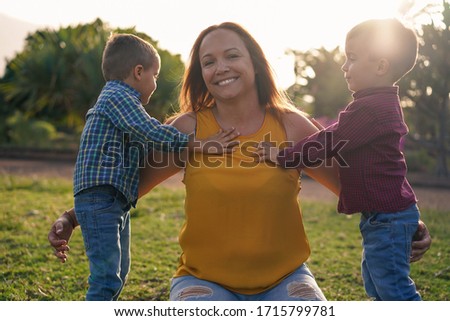 Young mother in a natural park with her twin sons - Mothers day - Young family enjoy time togheter - Family and love concept