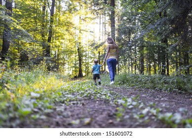 Young Mother On A Walk In Nature With Her Toddler Son.