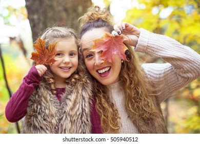 A Young mother playing with her daughter in autumn park
