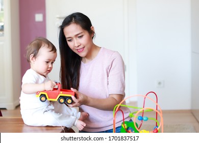 Young Mother Playing Toy Car With Her Little Baby At Home. Kid Smart Learning And Play Mixed Race Family Asian-German.