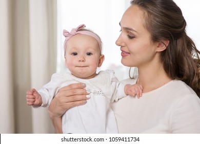 A young mother plays with a baby. A woman plays with a baby eight months of age