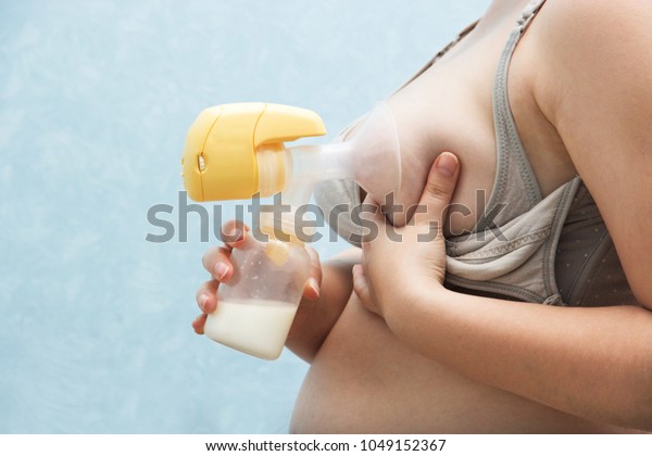 Young mother pumped breast milk. pump works on\
batteries, convenient to use. Breast milk for supplementary\
feeding, infant nutrition. feeding bra with detachable valves.\
Breast Pump in Female\
Hand.