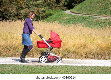 Young Mother Pushing Pram In Park On Sunny Day