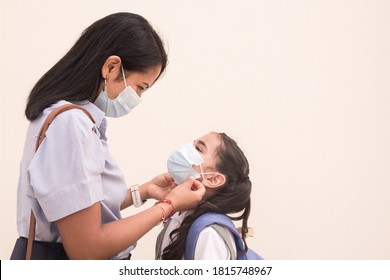 Young mother puts the mask on her daughter to prevent coronavirus. Hygiene and safety concept on back to school. Photography with copy space on isolated background. - Powered by Shutterstock