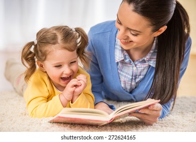 Young mother is reading a book to her cute daughter.