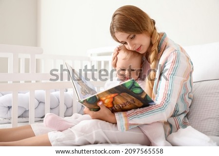 Similar – Mother reading book to her sons in the bed